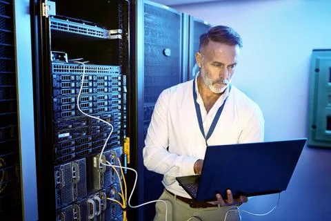 Internet, programmer and man in server room, laptop and problem solving with Stock-Fotos