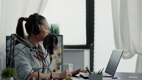 Internet radio show host talking on microphone while checking subject list on Vidéo 220810539