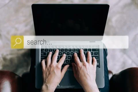 Internet search bar on the background of a man working on a laptop. Stock Photos