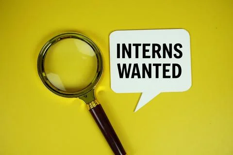 Interns Wanted text on speech bluble with magnifying glass top view on yell.. 스톡 사진