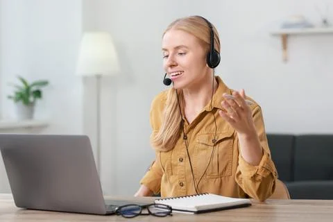 Interpreter in headset having video chat via laptop at table indoors Stock Photos