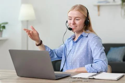 Interpreter in headset having video chat via laptop at table indoors Stock Photos