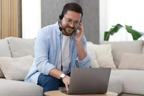 Interpreter in headset having video chat via laptop at wooden table indoors Stock Photos