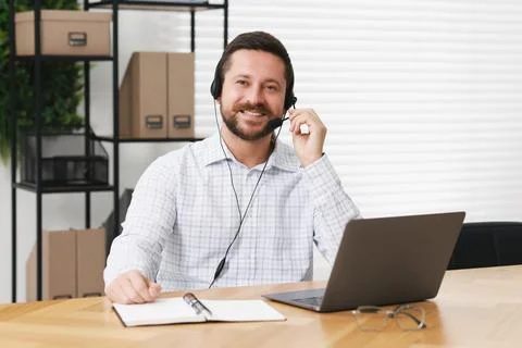 Interpreter in headset having video chat via laptop at wooden table indoors Stock Photos
