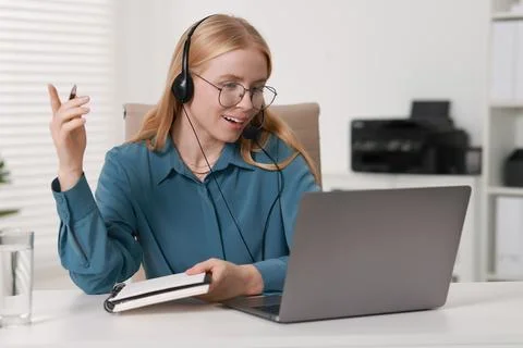 Interpreter in headset having video chat via laptop at table indoors Stock Photos