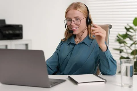 Interpreter in headset having video chat via laptop at table indoors Stock Photos