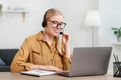 Interpreter in headset having video chat via laptop at table indoors Stock Photos
