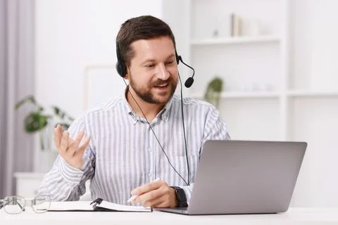 Interpreter in headset taking notes while having video chat via laptop at w.. Stock Photos