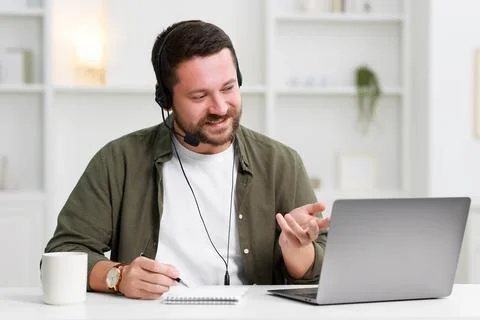 Interpreter in headset taking notes while having video chat via laptop at w.. Stock Photos