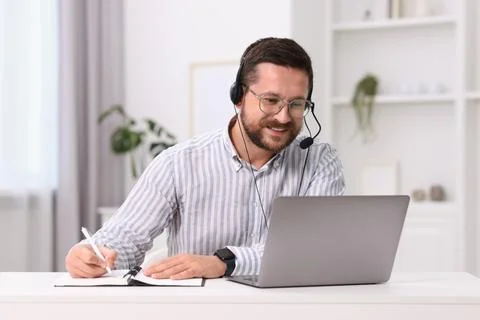 Interpreter in headset taking notes while having video chat via laptop at w.. Stock Photos