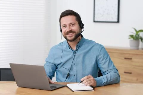 Interpreter in headset taking notes while having video chat via laptop at w.. Stock Photos