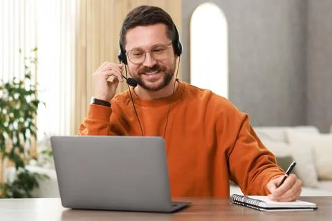 Interpreter in headset taking notes while having video chat via laptop at w.. Stock Photos