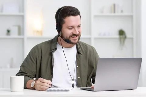 Interpreter in headset taking notes while having video chat via laptop at w.. Stock Photos