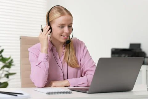 Interpreter in headset working with laptop at table indoors Stock Photos
