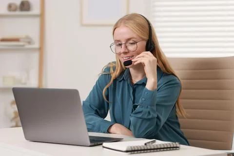 Interpreter in headset working with laptop at table indoors Stock Photos