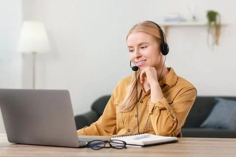 Interpreter in headset working with laptop at table indoors Stock Photos