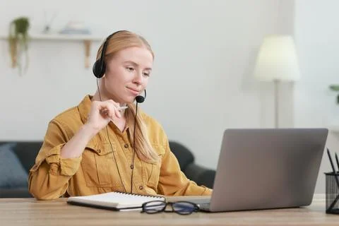 Interpreter in headset working with laptop at table indoors Stock Photos
