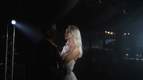 Interracial couple dancing first wedding dance in darkened reception hall Stock Footage 302726675