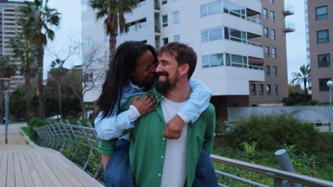 Interracial couple having fun in the city, piggyback ride and laughter Stock Footage 315874707