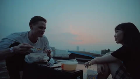 Interracial couple having a rooftop dinner at sunset Stockbeeldmateriaal 335045098