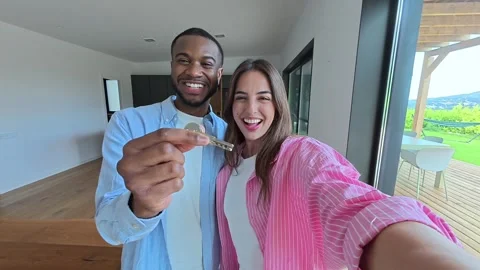 Interracial couple holding keys taking selfie in Stock Footage 334636456
