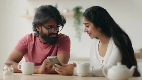 Interracial couple in kitchen using mobile phone diverse woman girl and man guy 스톡 동영상 243450894