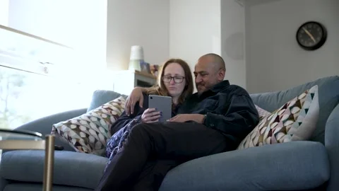 Interracial couple relaxing on sofa using digital tablet Vídeos de archivo 304684589