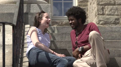An interracial couple sit on school steps and talk. Stock Footage 44117373