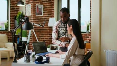 Interracial creative team programing code on a laptop and debugging Stock Footage 319719320