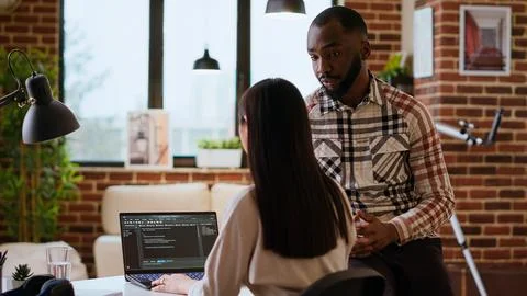 Interracial creative team programing code on a laptop and debugging Stock Photos
