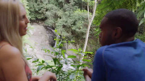 Interracial friends talking in front of small waterfall in an Australian rainfor Stock Footage 199457833