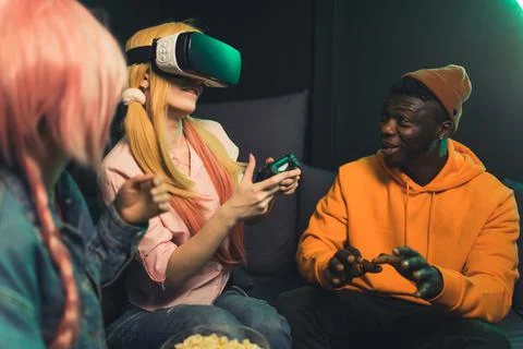 Interracial group of gamer friends trying out virtual reality goggle set for the Stock Photos