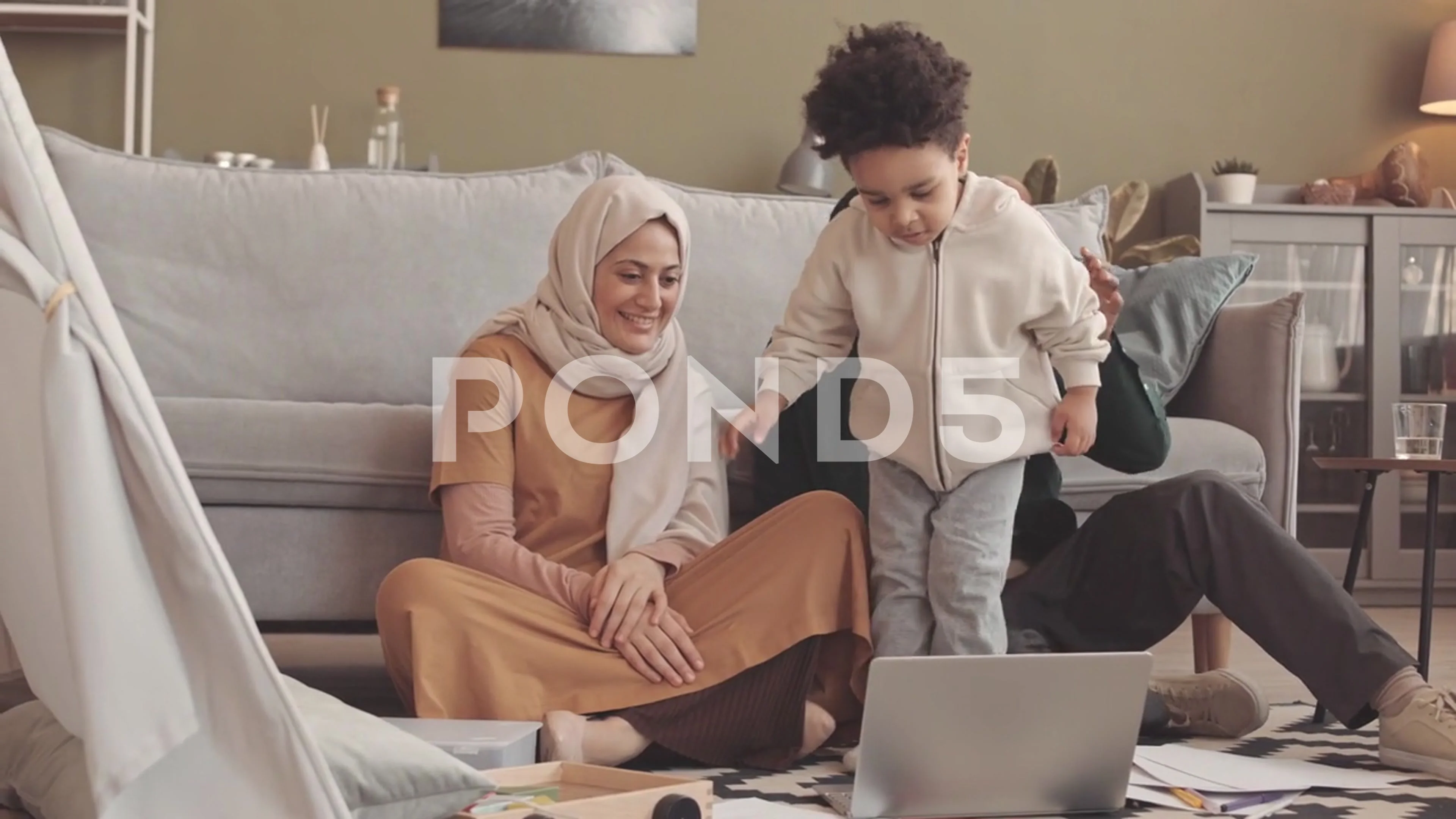 Interracial Muslim Family of Three Video Chatting on Laptop from Home