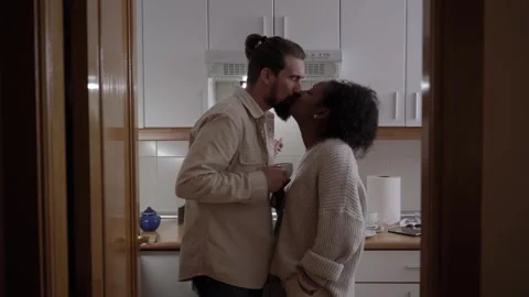 Interracial young couple at home drinking coffee and speaking while embracing. Stock Footage 262777399