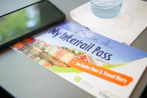 Interrail pass. Located next to a mobile and a glass of water. Stock Photos