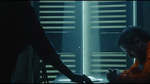 Interrogator recording bearded prisoner in a dark room Stock Footage 275085499