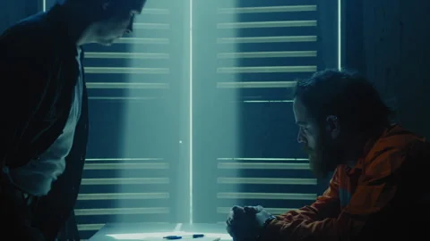 Interrogator sitting in front of prisoner in a dark room Stock Footage 275085764