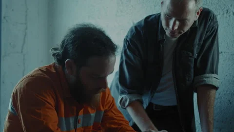 Interrogator talking to prisoner in a small dark room Stock Footage 275026662