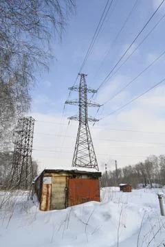 Intersecting high-voltage power lines on the snowy outskirts of city in winter Stock Photos