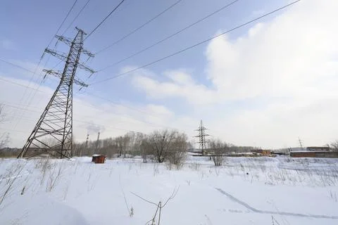 Intersecting high-voltage power lines on the snowy outskirts of city in winter Stock Photos