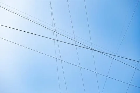 Intersecting power lines forming a grid pattern against a clear blue sky Stock Photos