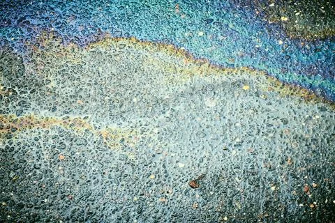 Intersecting rainbow colors creating abstract patterns on wet asphalt texture Stock Photos