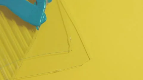Intersecting sheets with poured blue paint, geometric abstract on yellow Stock Footage 316612884