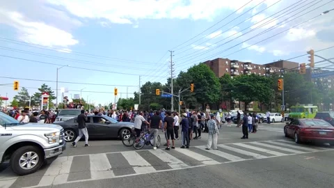 Intersection blocked by people protesting in Malton, Mississauga, Canada Stock Footage 136854324
