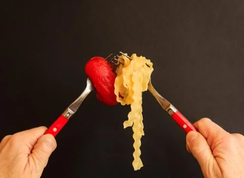 An intersection of two forks with noodles and  tomato 스톡 사진