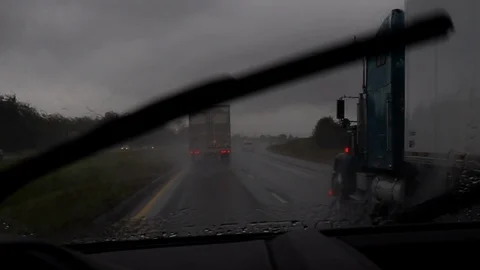 Interstate driving with trucks in rain Stock Footage 97527174