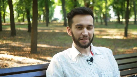 Interview with a handsome young man in the park for a blog. Small talk with a Stock Footage 203915205