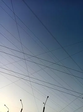 Interweaving network of electrical wires against the background of the blue sky Stock Photos