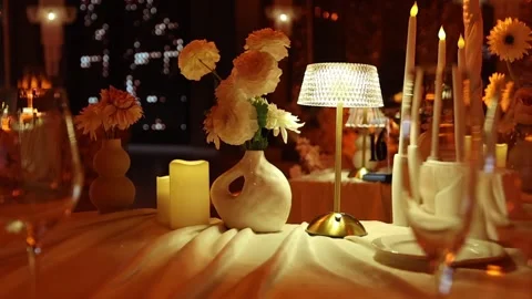 Intimate candlelit table with ceramic vases, textured lamp, and flickering Stock Footage 346083382
