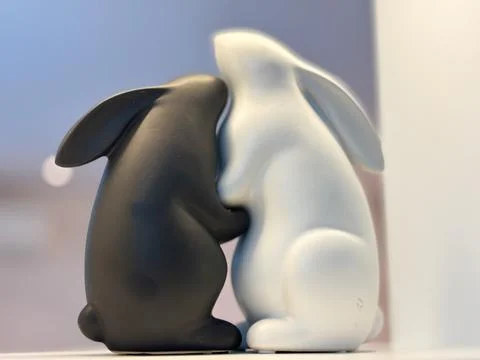 Intimate close-up of two ceramic or resin rabbit figurines embracing. Stock Photos